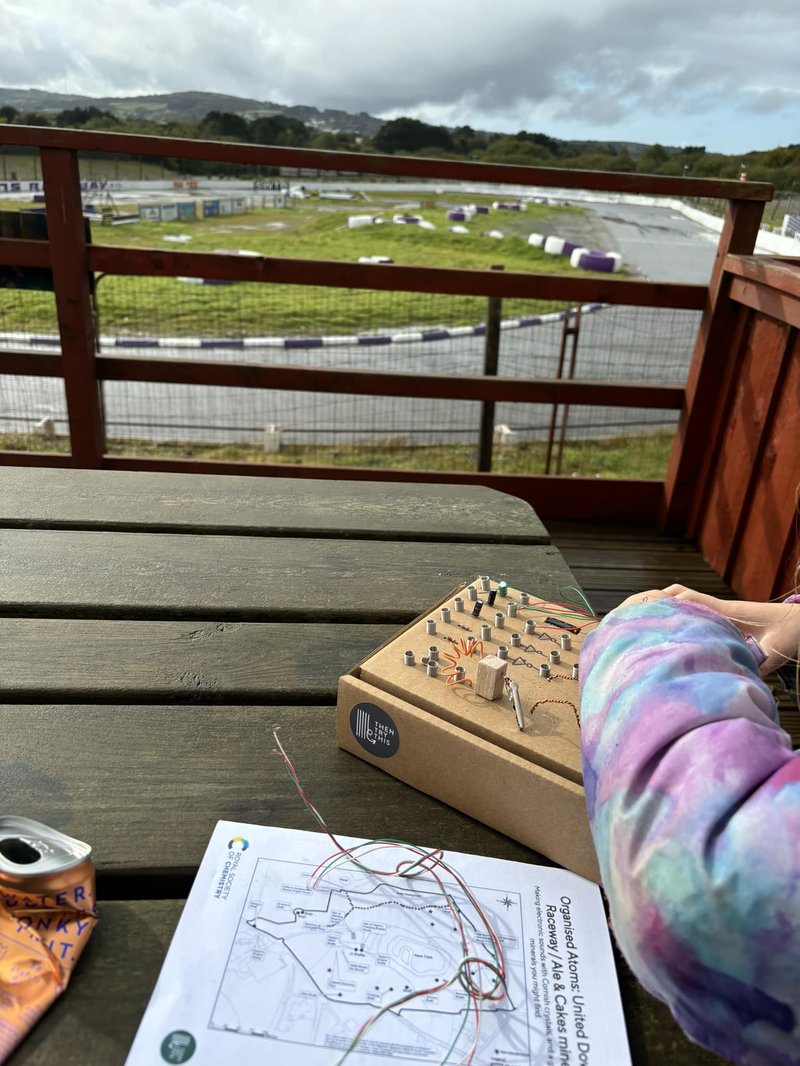 A cardboard synth on a picnic table with a race track in the distance